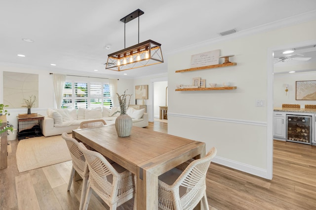 769 Berkeley St, Boca Raton, FL 33487 - dining space featuring beverage cooler, ornamental molding, light wood finished floors, recessed lighting, and a bar