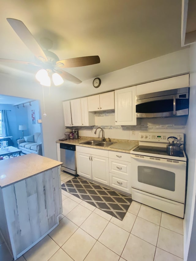 3093 SW Berry Ave, Palm City, FL 34990 - kitchen featuring appliances with stainless steel finishes, a sink, white cabinetry, light tile patterned floors, and light countertops