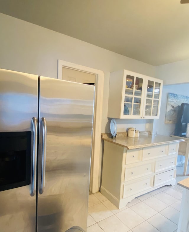 3093 SW Berry Ave, Palm City, FL 34990 - kitchen with stainless steel fridge, glass insert cabinets, light tile patterned floors, and white cabinets