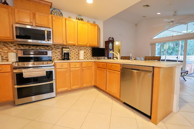 4245 Bluff Harbor Way, Wellington, FL 33449 - kitchen with stainless steel appliances, light countertops, tasteful backsplash, a peninsula, and light tile patterned flooring