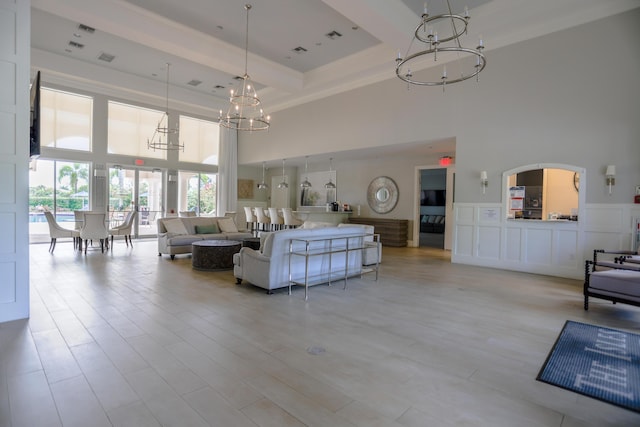 4245 Bluff Harbor Way, Wellington, FL 33449 - living room featuring a chandelier, a towering ceiling, beamed ceiling, light wood-type flooring, and ornamental molding