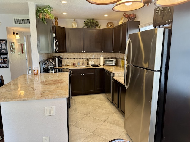 478 Capri J, Delray Beach, FL 33484 - kitchen featuring appliances with stainless steel finishes, a sink, backsplash, dark brown cabinets, and a peninsula