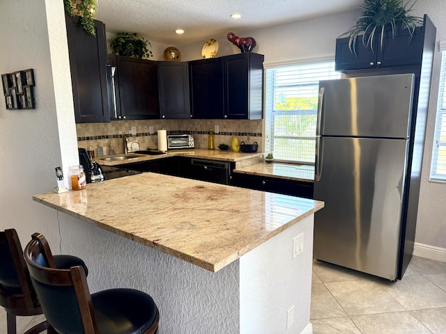 478 Capri J, Delray Beach, FL 33484 - kitchen with freestanding refrigerator, a peninsula, a breakfast bar, decorative backsplash, and a sink