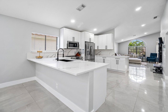 12350 Sand Wedge Dr, Boynton Beach, FL 33437 - kitchen with stainless steel appliances, a peninsula, a sink, light stone countertops, and lofted ceiling