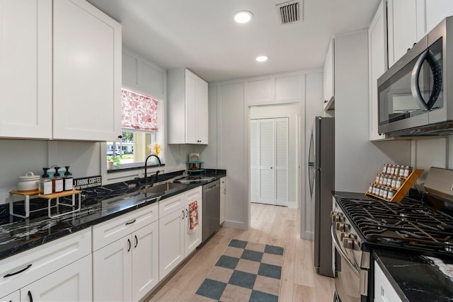 2948 SE Treasure Island Rd, Port Saint Lucie, FL 34952 - kitchen featuring appliances with stainless steel finishes, light wood-type flooring, white cabinets, recessed lighting, and dark stone counters