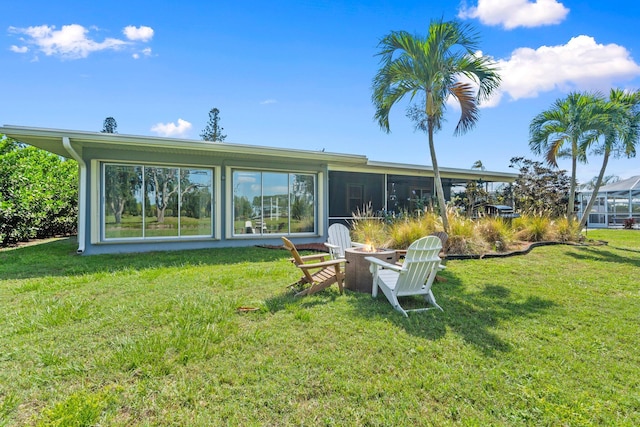 2948 SE Treasure Island Rd, Port Saint Lucie, FL 34952 - back of house with an outdoor fire pit, a lawn, and a sunroom