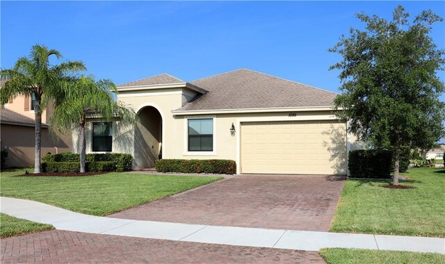 1095 N Verona Trace Dr, Vero Beach, FL 32966 - view of front of house featuring decorative driveway, stucco siding, a garage, and a front lawn