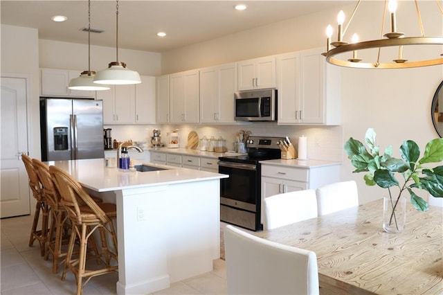1095 N Verona Trace Dr, Vero Beach, FL 32966 - kitchen featuring appliances with stainless steel finishes, a sink, white cabinetry, backsplash, and a center island with sink