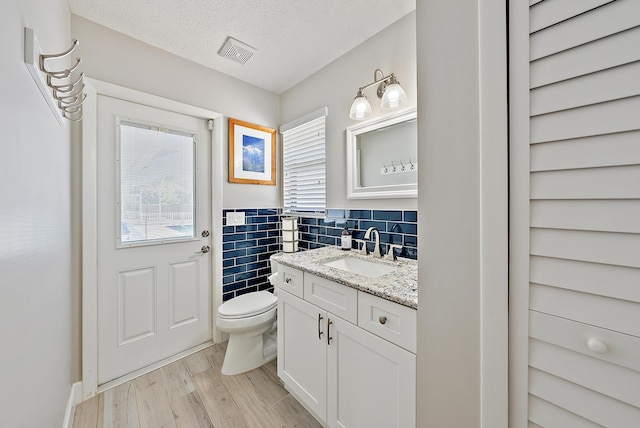 407 SE Duff Ct, Port Saint Lucie, FL 34984 - bathroom featuring vanity, toilet, wood finished floors, and a textured ceiling