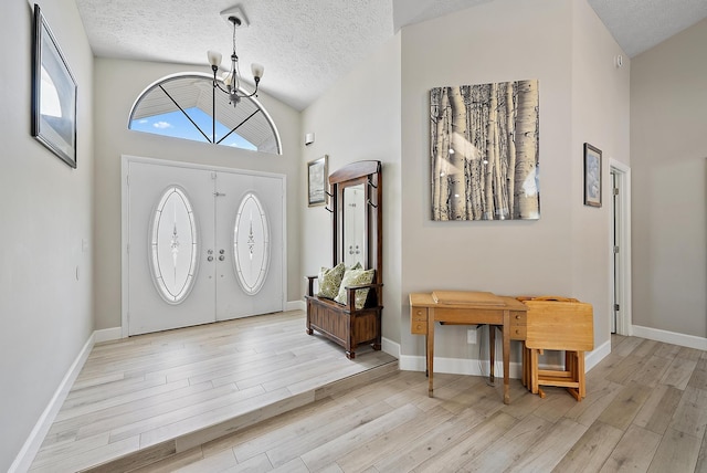407 SE Duff Ct, Port Saint Lucie, FL 34984 - entryway featuring a chandelier, vaulted ceiling, light wood finished floors, a textured ceiling, and baseboards