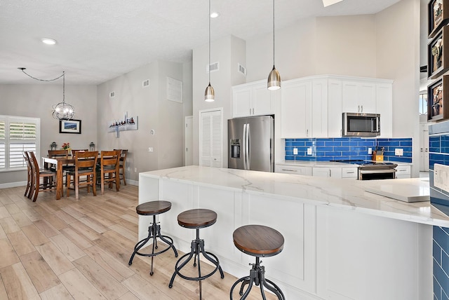 407 SE Duff Ct, Port Saint Lucie, FL 34984 - kitchen with stainless steel appliances, a towering ceiling, decorative backsplash, light wood-type flooring, and baseboards