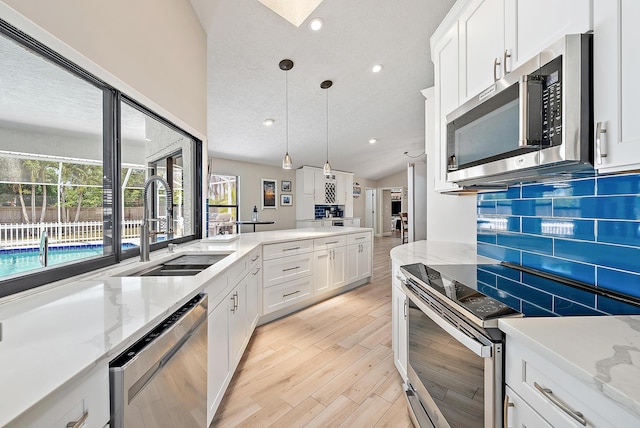 407 SE Duff Ct, Port Saint Lucie, FL 34984 - kitchen featuring stainless steel appliances, a sink, lofted ceiling, tasteful backsplash, and white cabinetry