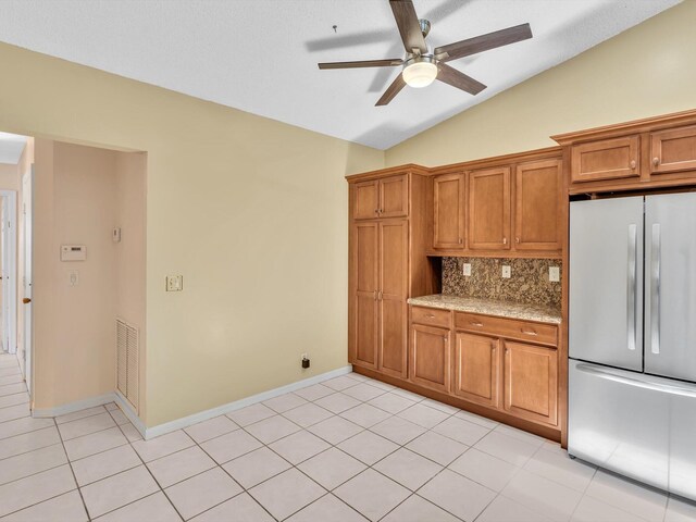 18458 Via Di Sorrento, Boca Raton, FL 33496 - kitchen with stainless steel fridge, ceiling fan, brown cabinets, tasteful backsplash, and vaulted ceiling