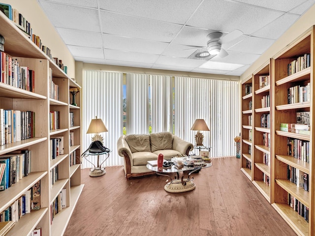 18458 Via Di Sorrento, Boca Raton, FL 33496 - living area featuring wall of books, a paneled ceiling, a ceiling fan, and wood finished floors