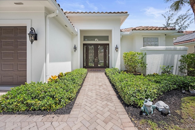 1770 Flagler Manor Cir, West Palm Beach, FL 33411 - doorway to property with french doors, a tile roof, a garage, and stucco siding