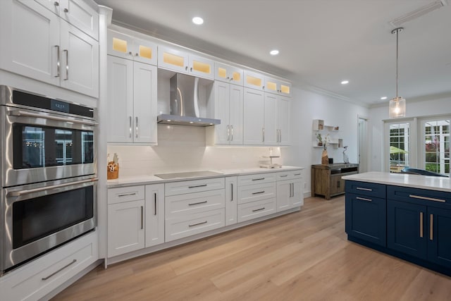 1770 Flagler Manor Cir, West Palm Beach, FL 33411 - kitchen with stainless steel double oven, wall chimney exhaust hood, blue cabinets, light countertops, and ornamental molding