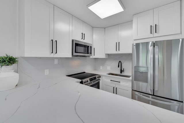 76 Mansfield B 76, Boca Raton, FL 33434 - kitchen featuring appliances with stainless steel finishes, a sink, decorative backsplash, and white cabinets