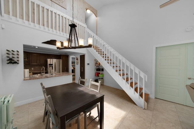 4099 Palm Bay Cir Unit A, West Palm Beach, FL 33406 - dining room featuring a towering ceiling, stairway, baseboards, a chandelier, and light tile patterned floors
