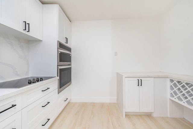 200 SW 48th Ave, Miami, FL 33134 - kitchen with stainless steel double oven, light wood-style floors, white cabinetry, and black electric stovetop