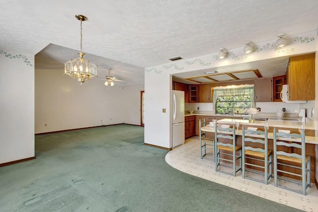 102 SE Crosspoint Dr, Port Saint Lucie, FL 34983 - kitchen featuring freestanding refrigerator, light colored carpet, baseboards, a chandelier, and a textured ceiling