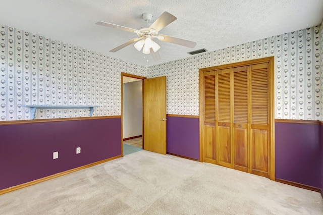 102 SE Crosspoint Dr, Port Saint Lucie, FL 34983 - unfurnished bedroom featuring wallpapered walls, a closet, carpet, ceiling fan, and a textured ceiling