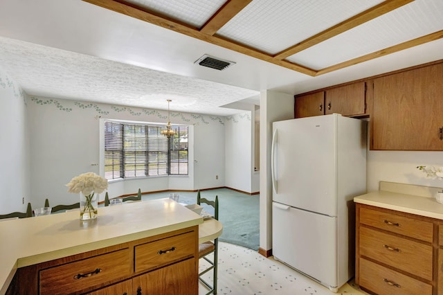102 SE Crosspoint Dr, Port Saint Lucie, FL 34983 - kitchen featuring freestanding refrigerator, light countertops, a kitchen bar, brown cabinetry, and decorative light fixtures