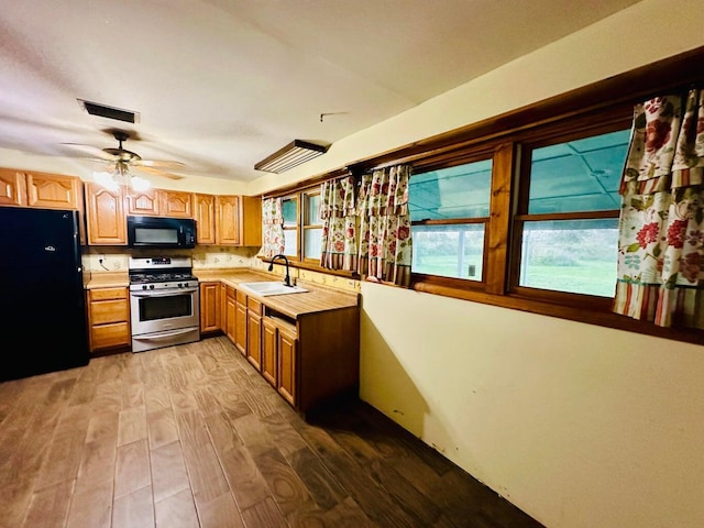 15255 NW 260th St, Okeechobee, FL 34972 - kitchen with black appliances, a sink, light countertops, wood finished floors, and ceiling fan
