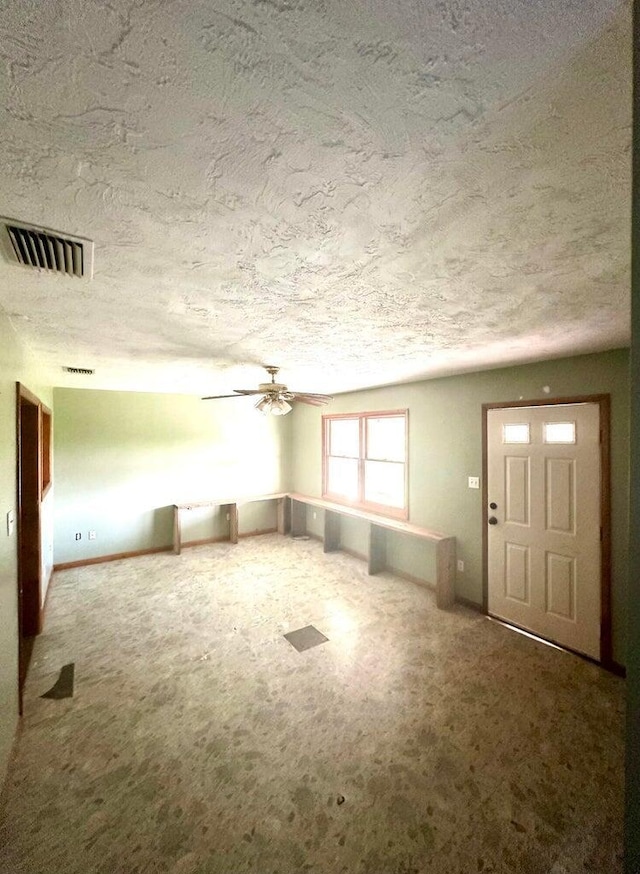 15255 NW 260th St, Okeechobee, FL 34972 - unfurnished living room featuring a textured ceiling, a ceiling fan, carpet floors, and baseboards