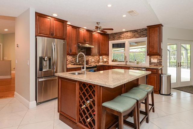 2610 SE Erickson Dr, Port Saint Lucie, FL 34984 - kitchen featuring stainless steel appliances, a sink, backsplash, light stone countertops, and under cabinet range hood