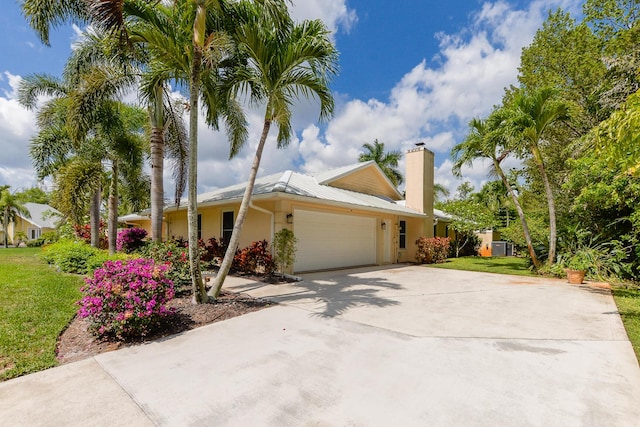 2610 SE Erickson Dr, Port Saint Lucie, FL 34984 - view of front of home with an attached garage, driveway, a front yard, and a chimney