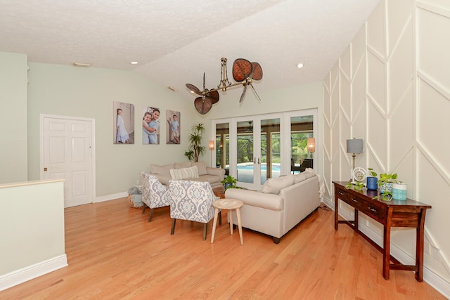 2610 SE Erickson Dr, Port Saint Lucie, FL 34984 - living room featuring french doors, light wood-style floors, vaulted ceiling, baseboards, and a textured ceiling