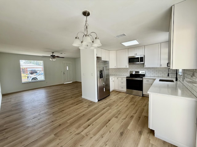 711 NW Riverside Dr, Port Saint Lucie, FL 34983 - kitchen with appliances with stainless steel finishes, a sink, open floor plan, backsplash, and light stone countertops