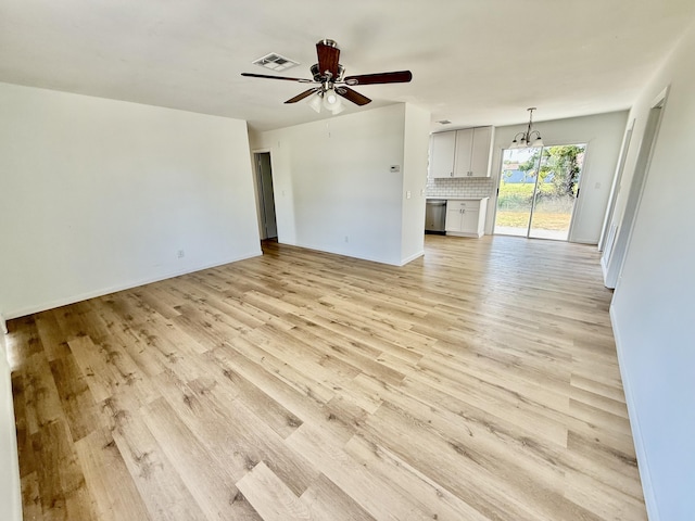 711 NW Riverside Dr, Port Saint Lucie, FL 34983 - unfurnished living room with a ceiling fan, light wood-style floors, and a chandelier