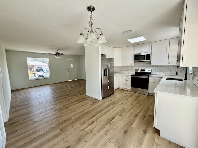 711 NW Riverside Dr, Port Saint Lucie, FL 34983 - kitchen with stainless steel appliances, a sink, light stone counters, backsplash, and open floor plan