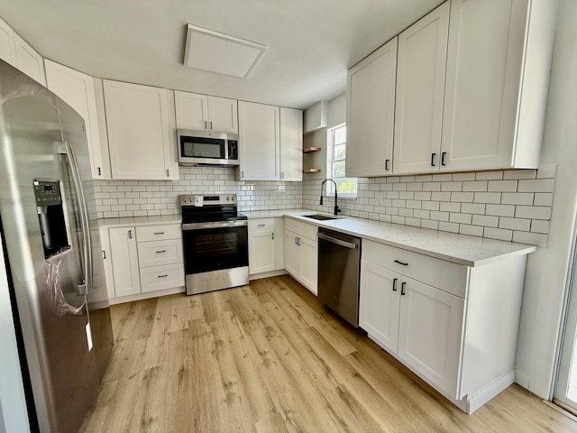 711 NW Riverside Dr, Port Saint Lucie, FL 34983 - kitchen featuring appliances with stainless steel finishes, a sink, open shelves, light wood-type flooring, and white cabinets