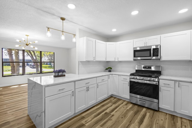 555 Benedictine Ter, Sebastian, FL 32958 - kitchen featuring stainless steel appliances, a peninsula, light wood-style flooring, white cabinets, and a textured ceiling