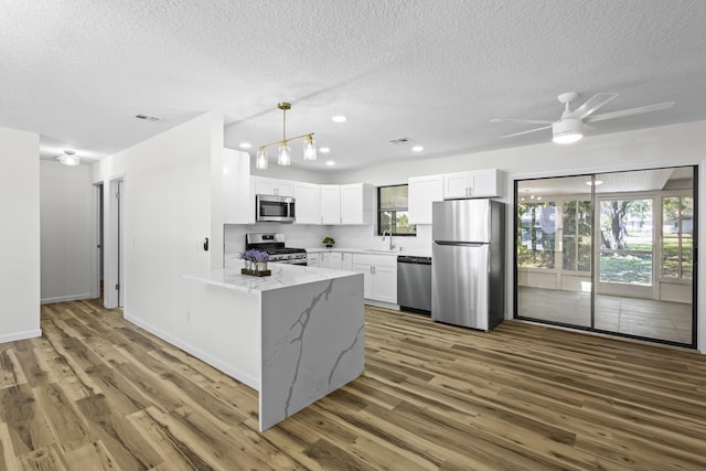 555 Benedictine Ter, Sebastian, FL 32958 - kitchen with stainless steel appliances, a sink, a peninsula, a textured ceiling, and light stone counters