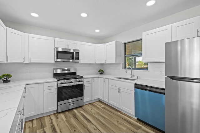 555 Benedictine Ter, Sebastian, FL 32958 - kitchen featuring appliances with stainless steel finishes, a sink, white cabinets, light wood-type flooring, and recessed lighting