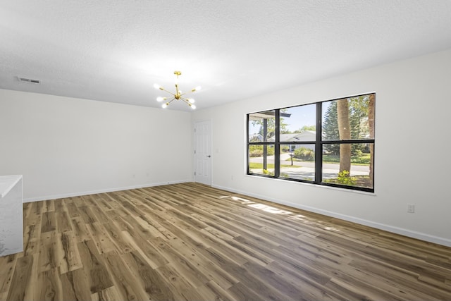 555 Benedictine Ter, Sebastian, FL 32958 - unfurnished room featuring a chandelier, wood finished floors, baseboards, and a textured ceiling