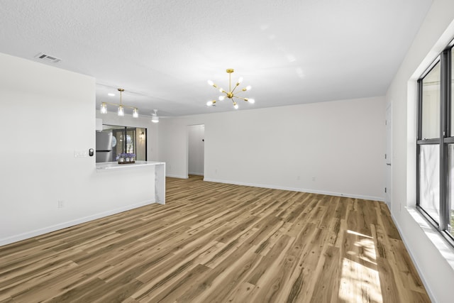 555 Benedictine Ter, Sebastian, FL 32958 - unfurnished living room featuring a chandelier, light wood-style floors, and baseboards