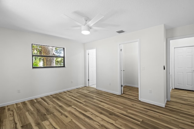 555 Benedictine Ter, Sebastian, FL 32958 - unfurnished bedroom with wood finished floors, baseboards, a ceiling fan, and a walk in closet