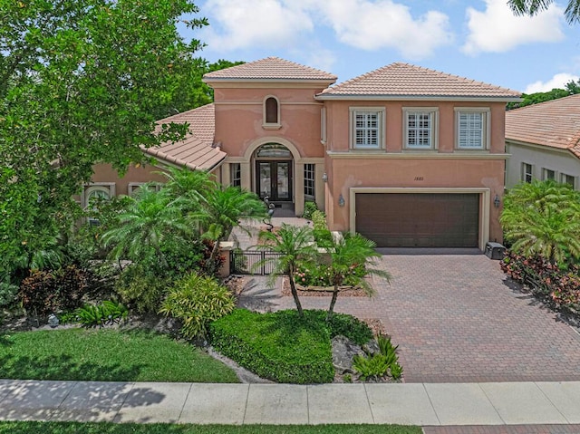 1885 Via Bellezza, Wellington, FL 33411 - mediterranean / spanish-style house with french doors, a tiled roof, stucco siding, a garage, and decorative driveway