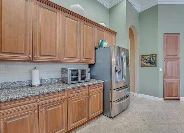 1885 Via Bellezza, Wellington, FL 33411 - kitchen with stainless steel fridge with ice dispenser, ornamental molding, backsplash, dark stone counters, and baseboards