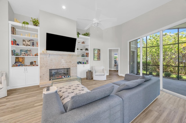 6304 SE Ames Way, Hobe Sound, FL 33455 - living room featuring light wood-style flooring, a ceiling fan, baseboards, a fireplace, and a high ceiling
