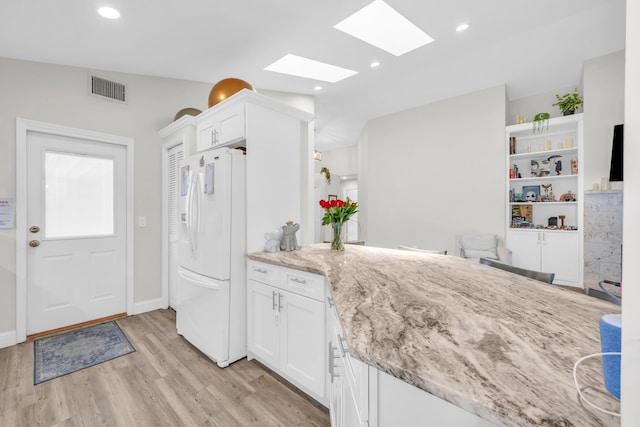 6304 SE Ames Way, Hobe Sound, FL 33455 - kitchen with white fridge with ice dispenser, a skylight, light wood-type flooring, white cabinets, and recessed lighting