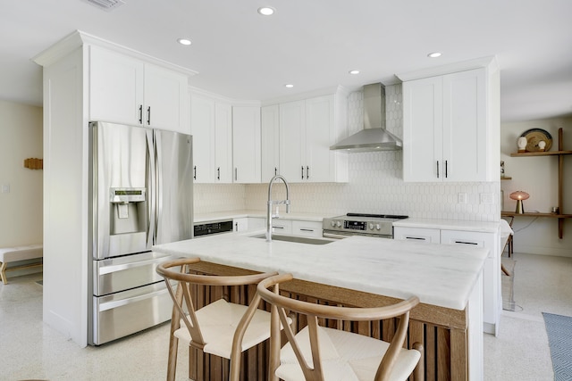 744 Eastwind Dr, North Palm Beach, FL 33408 - kitchen with stainless steel appliances, wall chimney range hood, a sink, baseboards, and a kitchen breakfast bar