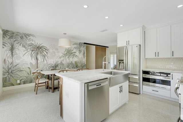 744 Eastwind Dr, North Palm Beach, FL 33408 - kitchen with appliances with stainless steel finishes, wallpapered walls, a sink, recessed lighting, and an island with sink