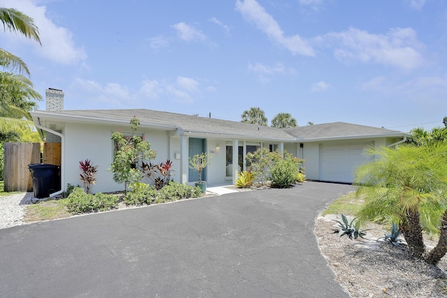 744 Eastwind Dr, North Palm Beach, FL 33408 - ranch-style home with an attached garage, a chimney, stucco siding, and asphalt driveway