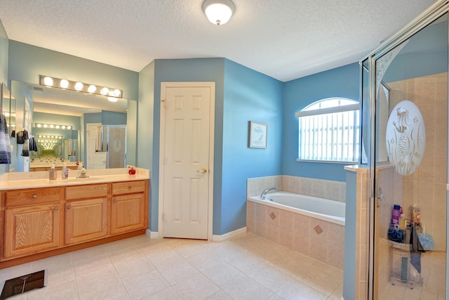 5940 NW Center St, Port Saint Lucie, FL 34986 - full bath with tile patterned floors, a garden tub, vanity, a shower stall, and a textured ceiling