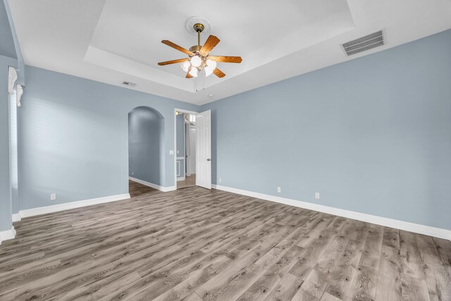 198 Magnolia Lakes Blvd, Port Saint Lucie, FL 34986 - empty room featuring a tray ceiling, ceiling fan, wood finished floors, baseboards, and arched walkways